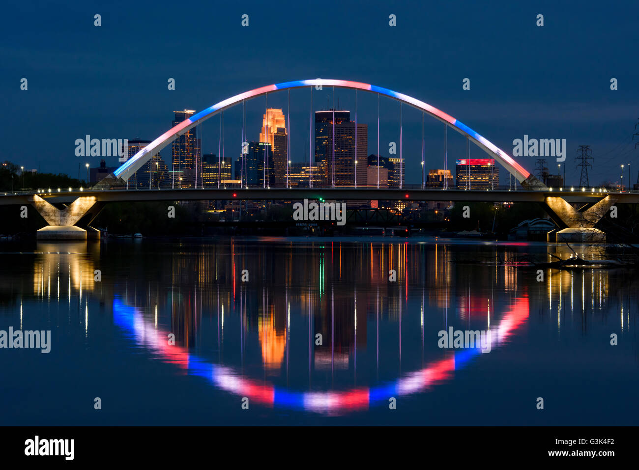 Minneapolis Minnesota skyline visto attraverso il Lowry Avenue bridge al tramonto con il blu e il rosso di illuminazione. Foto Stock