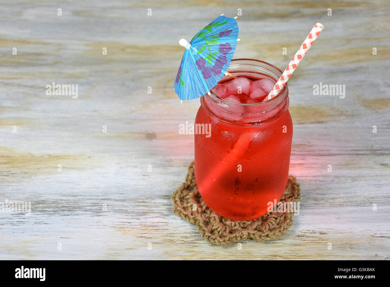 Punch alla frutta Bevande con ombrello di carta e paglia gingham in vetro mason jar sul legno stagionato. Foto Stock