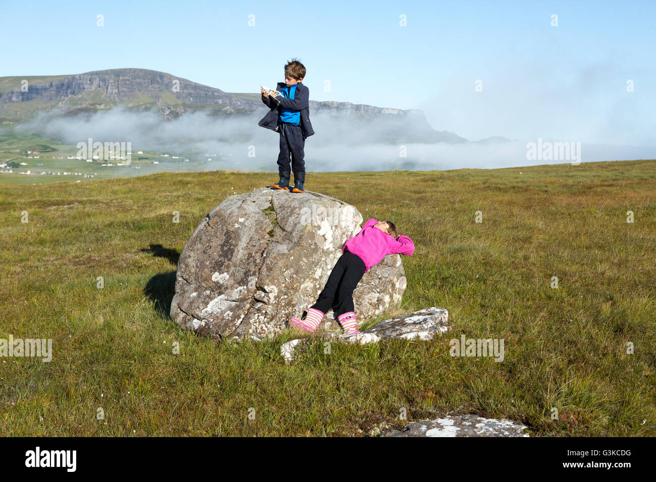 Ragazza rilassante su una roccia e ragazzo la lettura di una mappa durante una passeggiata in campagna sull'Isola di Skye, Ebridi Interne, Scotland, Regno Unito Foto Stock