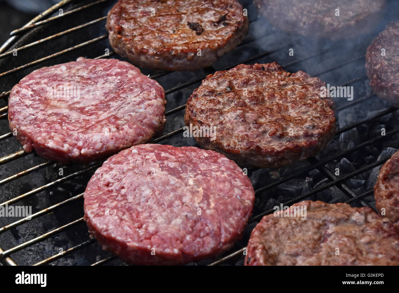 Materie e mezzo raro manzo cotto o carne di maiale barbecue hamburger per hamburger preparato alla griglia su fumo barbecue grill, close up Foto Stock