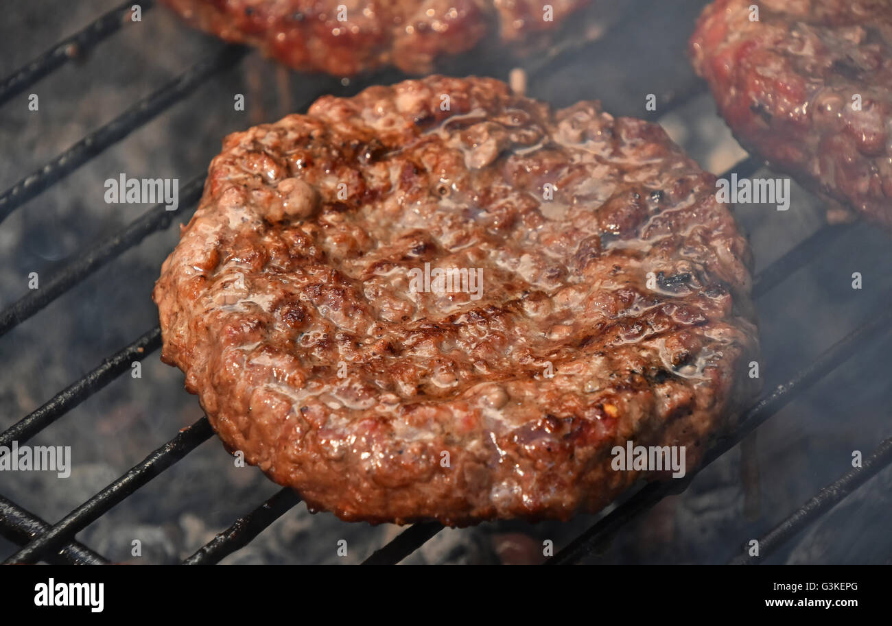 Carni bovine o le carni di maiale barbecue ben fatto hamburger per hamburger preparato alla griglia su fumo barbecue grill, close up Foto Stock