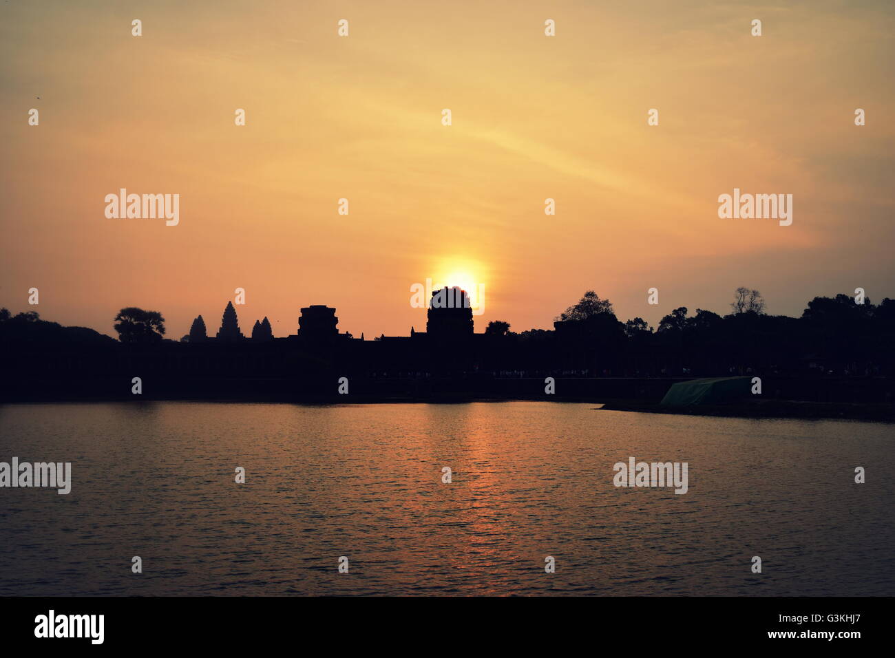 Il sorgere del sole dietro la silhouette di Angkor Wat in Cambogia oltre il tumulo Foto Stock