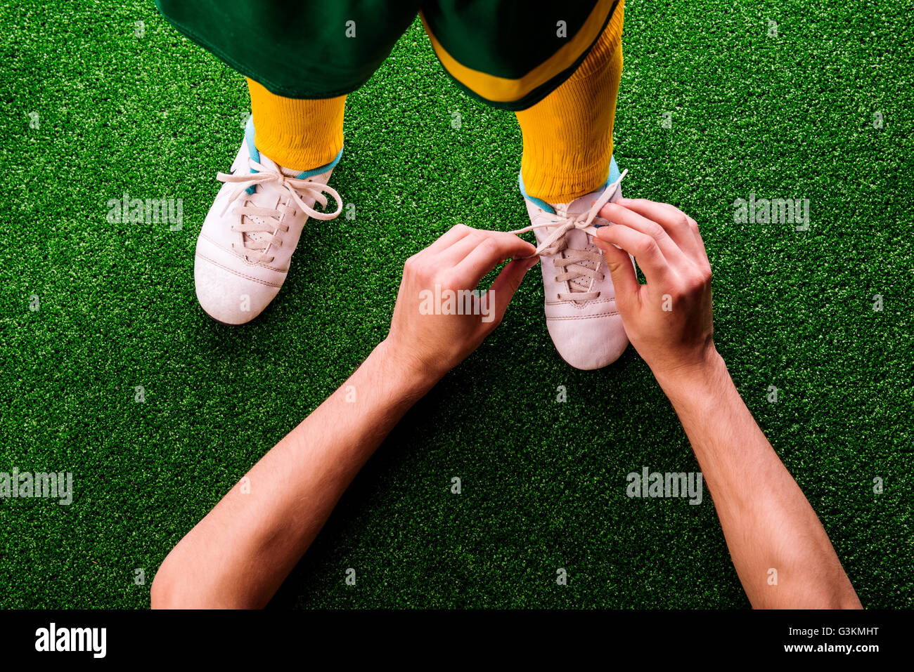 Padre irriconoscibile la legatura lacci delle scarpe a suo figlio, calcio Foto Stock