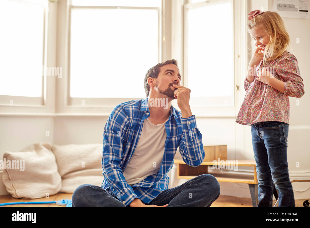 Giovane ragazza guardando il suo padre, con espressione maliziosa Foto Stock