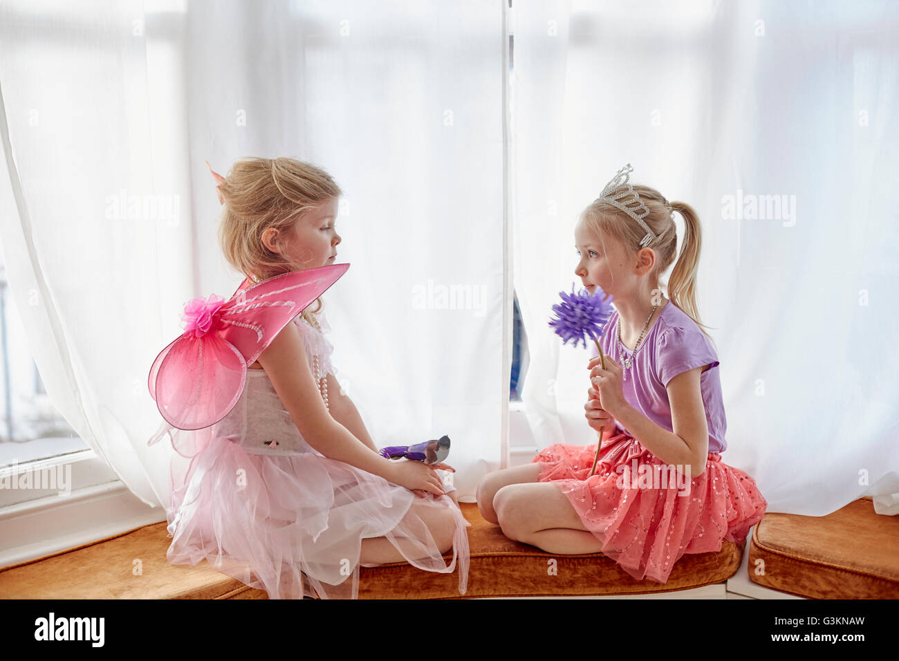Due ragazze in costume, seduta faccia a faccia Foto Stock