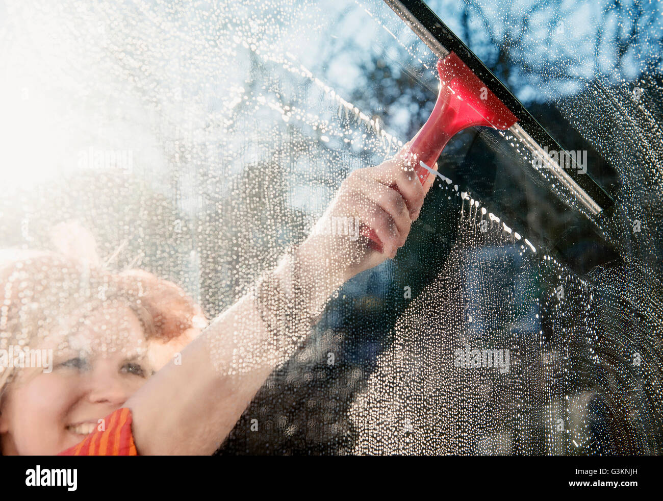 Donna di pulizia esterno soleggiato finestra con ventosa Foto Stock
