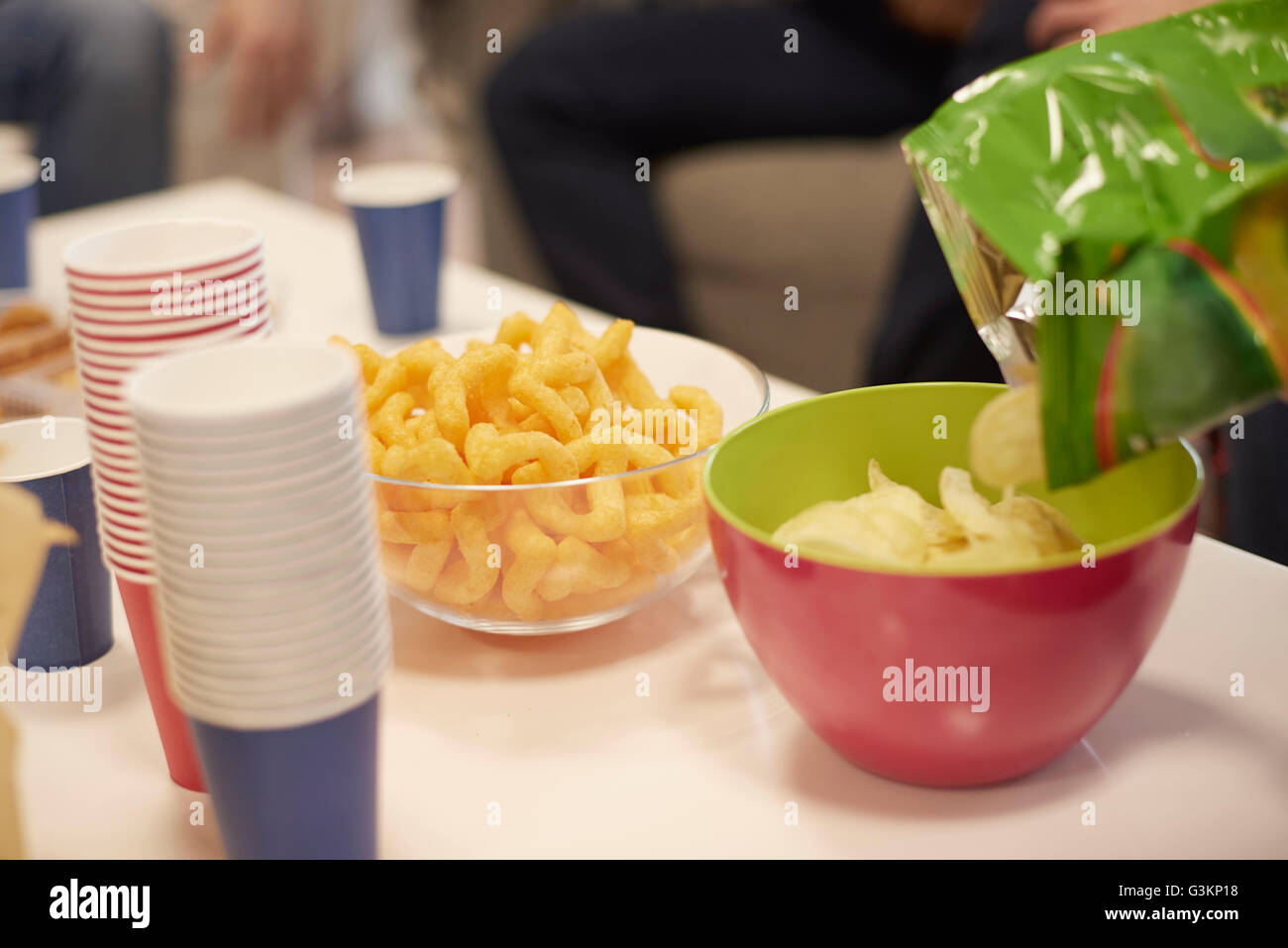 Vista ritagliata della tabella con tazze monouso e ciotole di potato chips e snacks Foto Stock