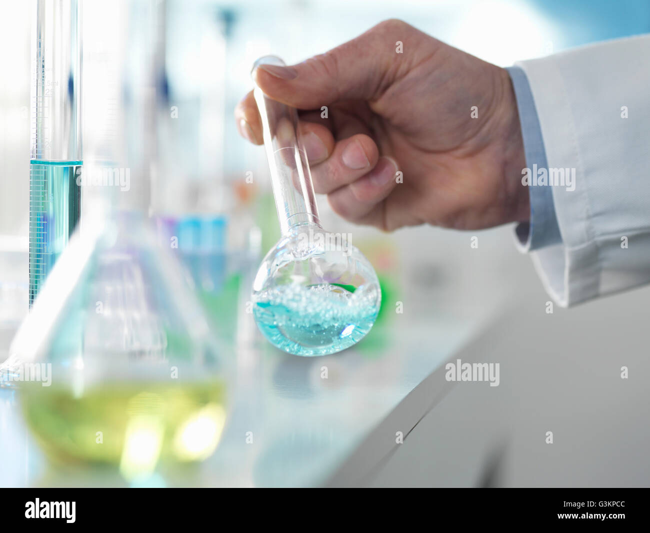 Scienziato preparando una formula chimica in una beuta conica durante un esperimento in laboratorio Foto Stock