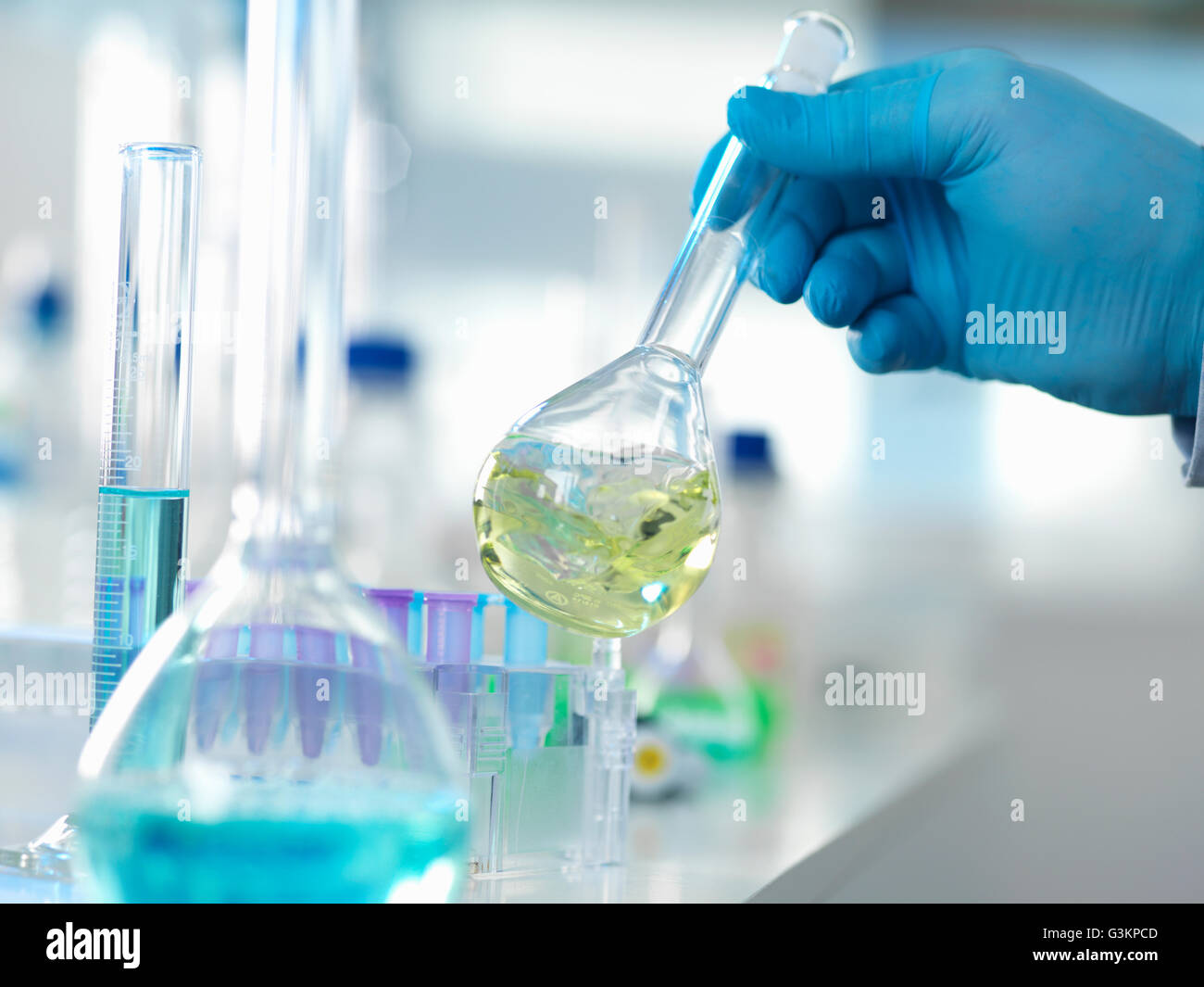 Scienziato preparando una formula chimica in una beuta conica durante un esperimento in laboratorio Foto Stock