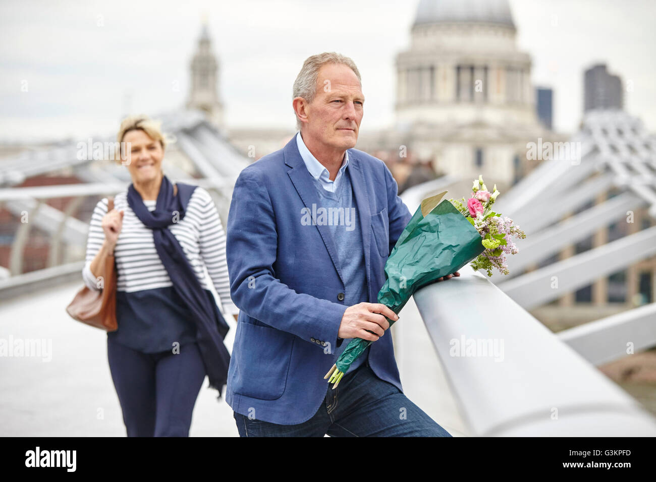 Uomo maturo con bouquet in attesa nella parte anteriore della data sul Millennium Bridge, London, Regno Unito Foto Stock