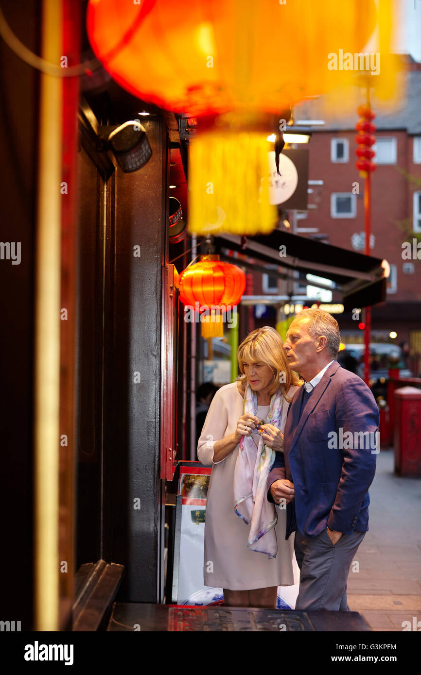 Coppia matura leggendo il menu del ristorante a China Town al crepuscolo, London, Regno Unito Foto Stock