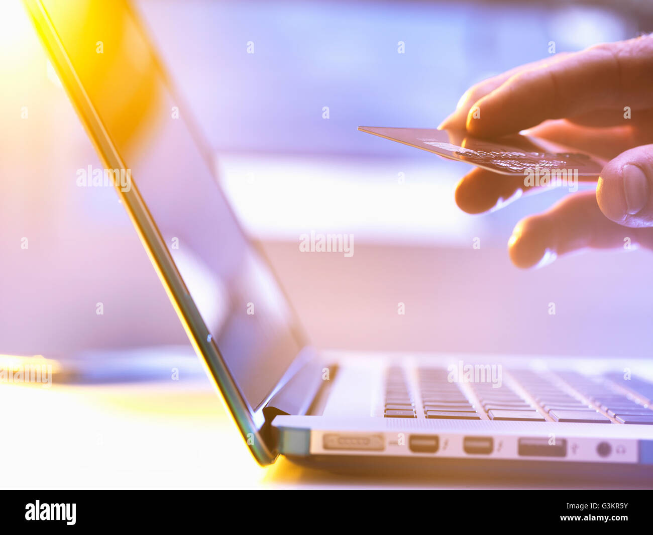 Uomo che utilizza la sua carta di credito online per lo shopping e banking con la luce del sole proveniente attraverso la finestra Foto Stock