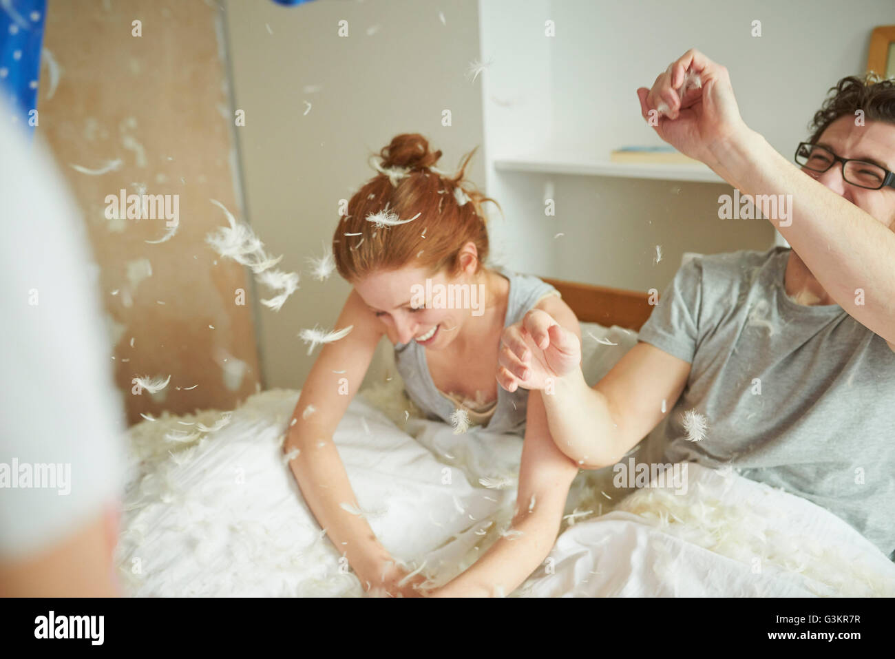 Metà adulto giovane avente cuscino lotta con la figlia nel letto Foto Stock
