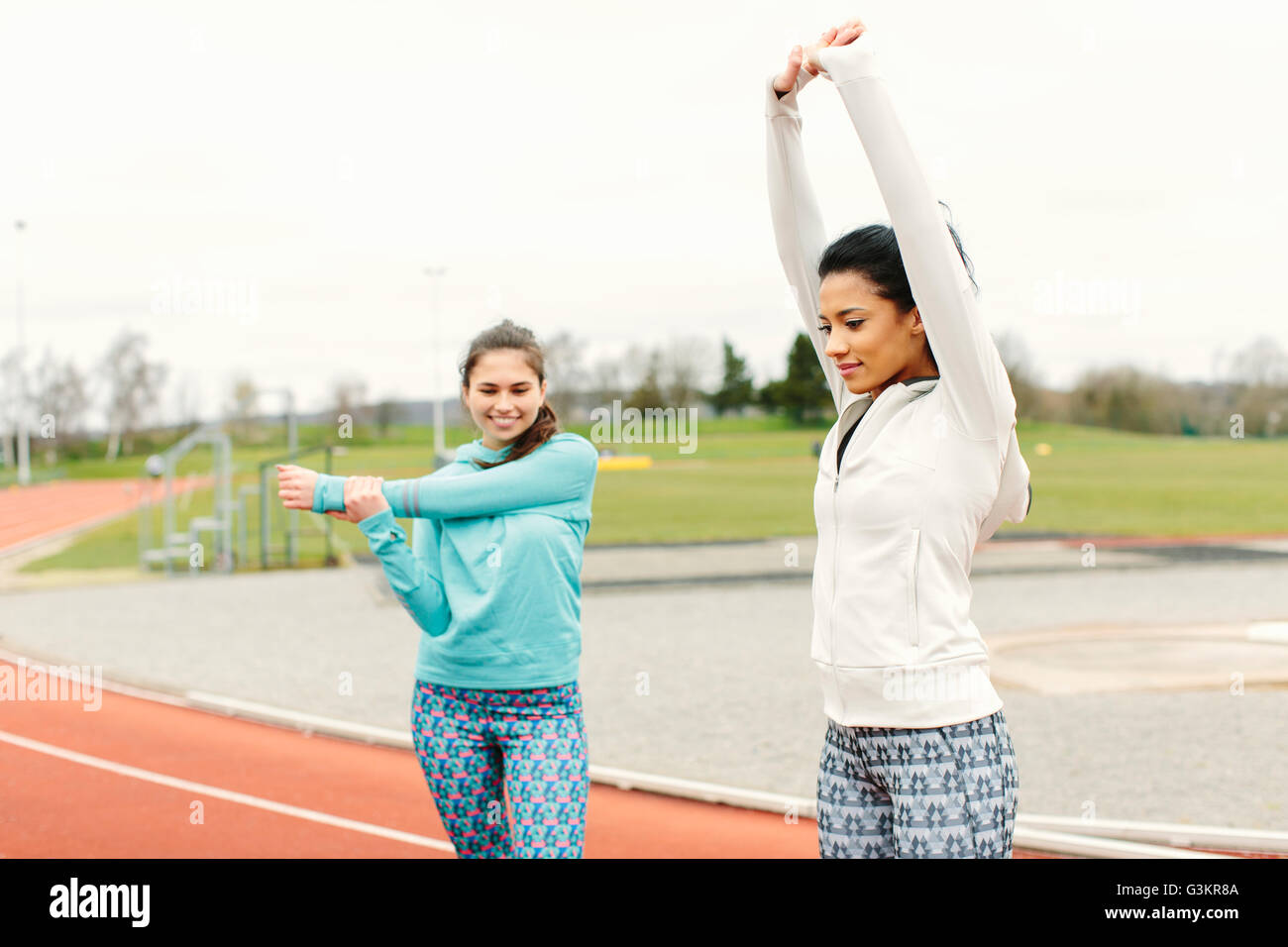 Due giovani donne sulla via di corsa, esercitando, stretching Foto Stock