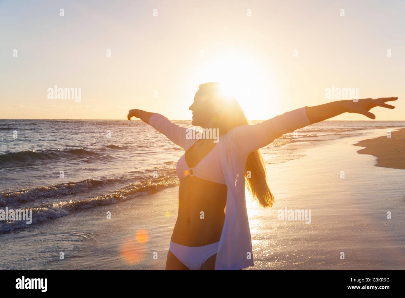 Giovane donna ballare con i bracci aperti sulla spiaggia al tramonto, Repubblica Dominicana, Caraibi Foto Stock