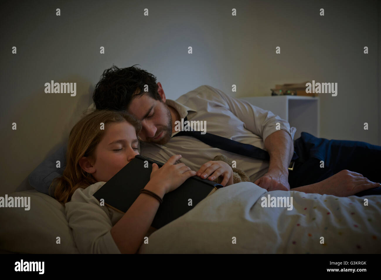 Imprenditore e figlia con storybook dormire sul letto Foto Stock