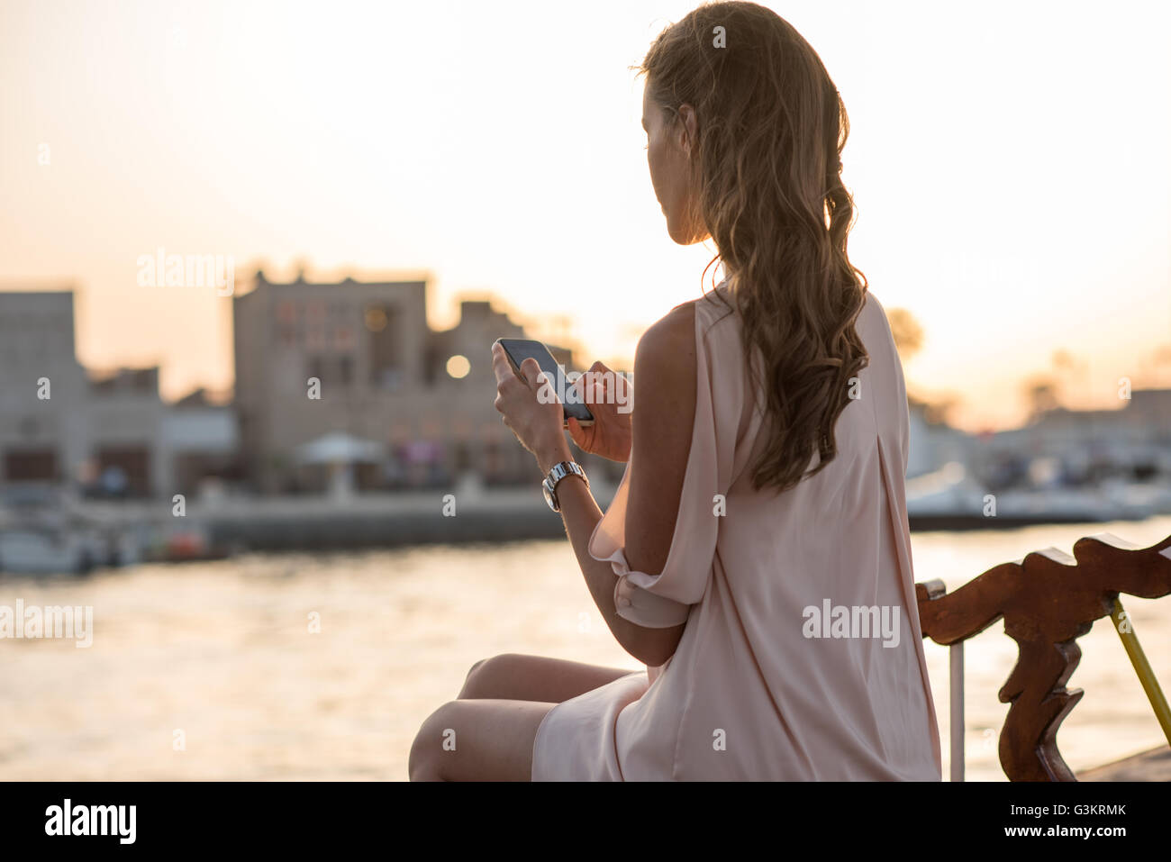 La donna lo smartphone la lettura di testi sulla barca nel porticciolo turistico di Dubai, Emirati Arabi Uniti Foto Stock