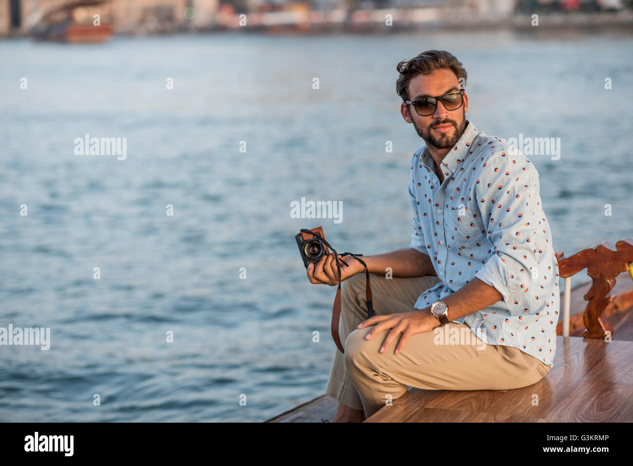 Giovane uomo guardando indietro dalla barca nel porticciolo turistico di Dubai, Emirati Arabi Uniti Foto Stock