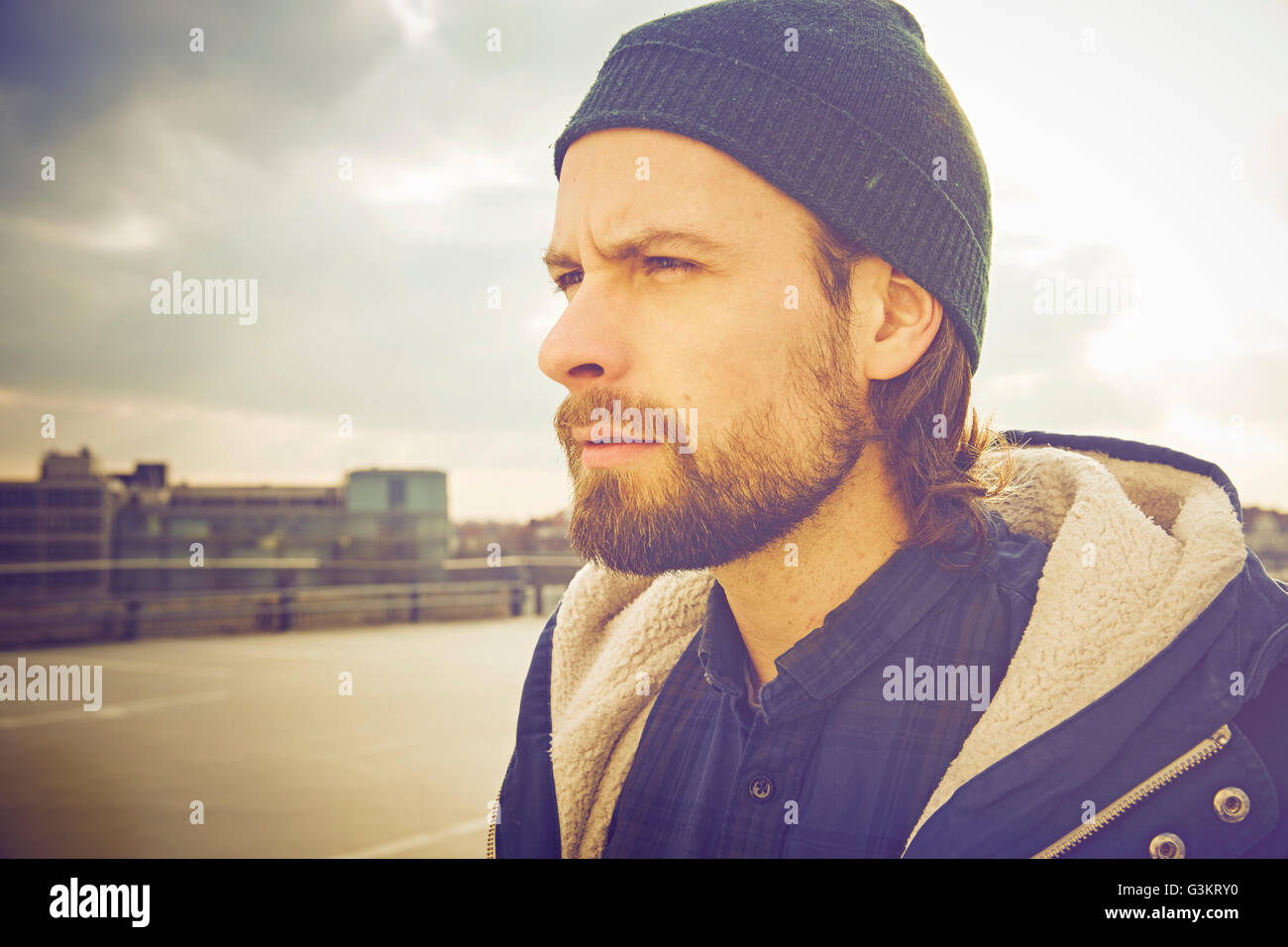 Ritratto di metà uomo adulto che indossa knit hat sul tetto parcheggio Foto Stock