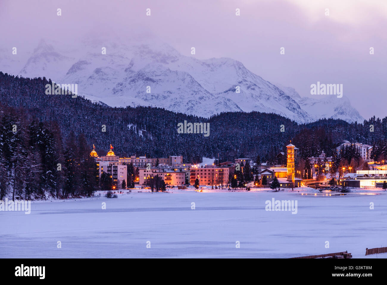 Villaggio sotto la montagna su paesaggi innevati illuminata di sera, Sankt Moritz, Svizzera Foto Stock