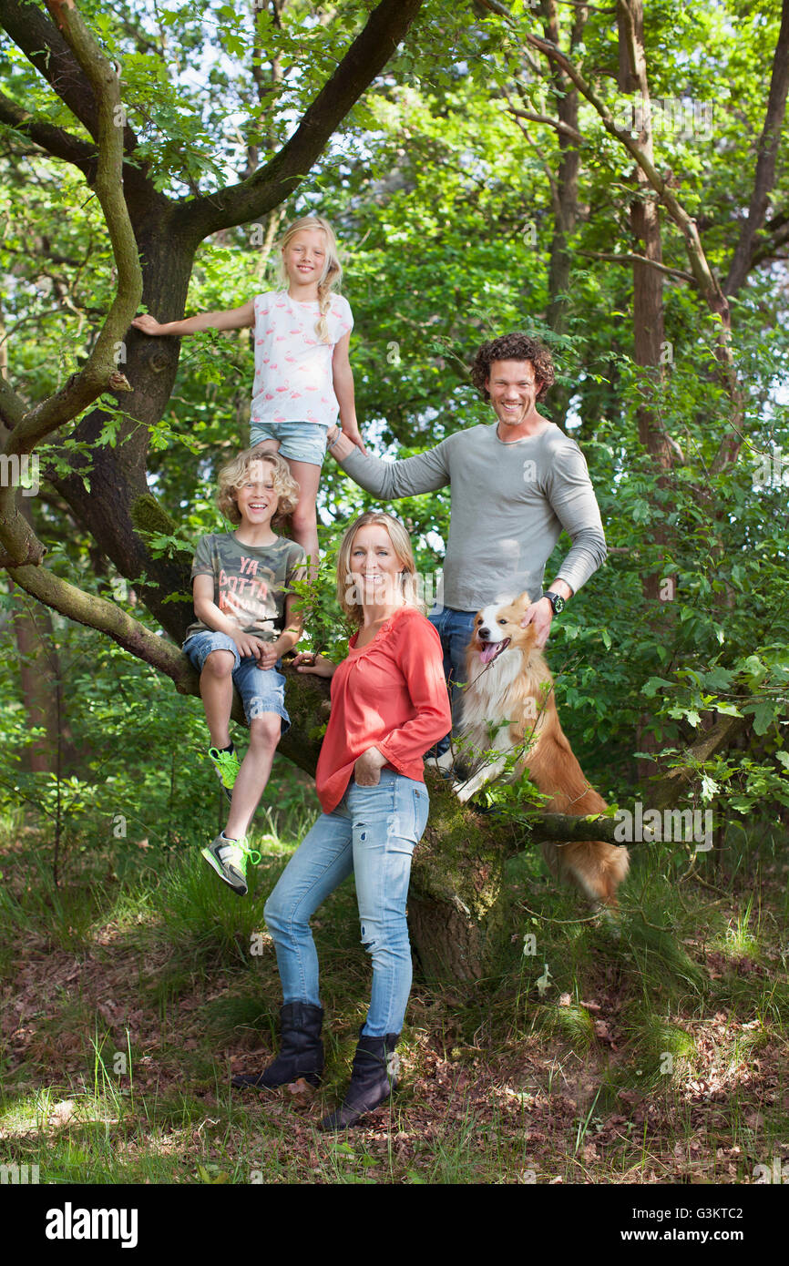 Famiglia nella foresta rampicante guardando sorridente della fotocamera Foto Stock