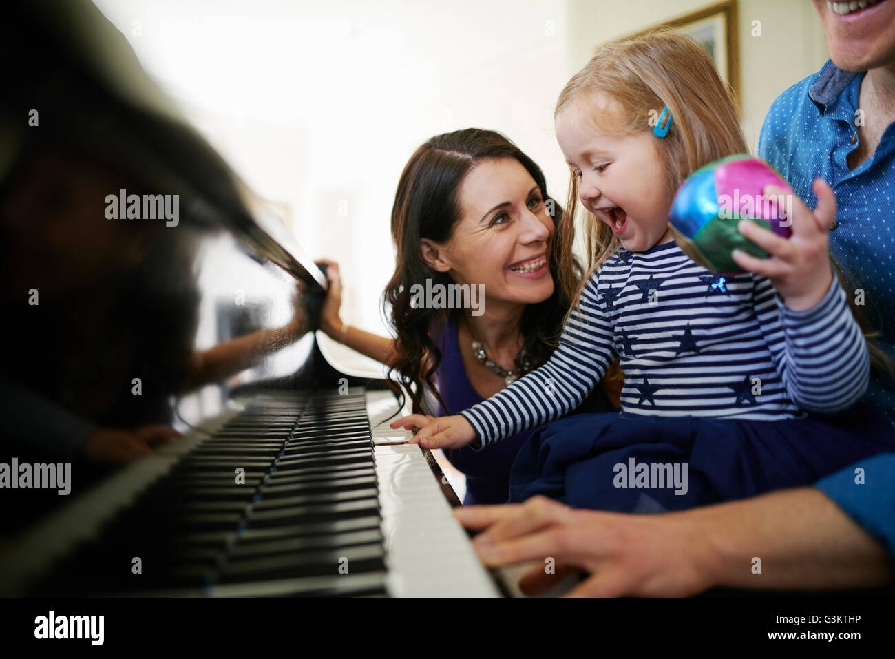 I genitori insegnare la figlia a suonare il piano Foto Stock