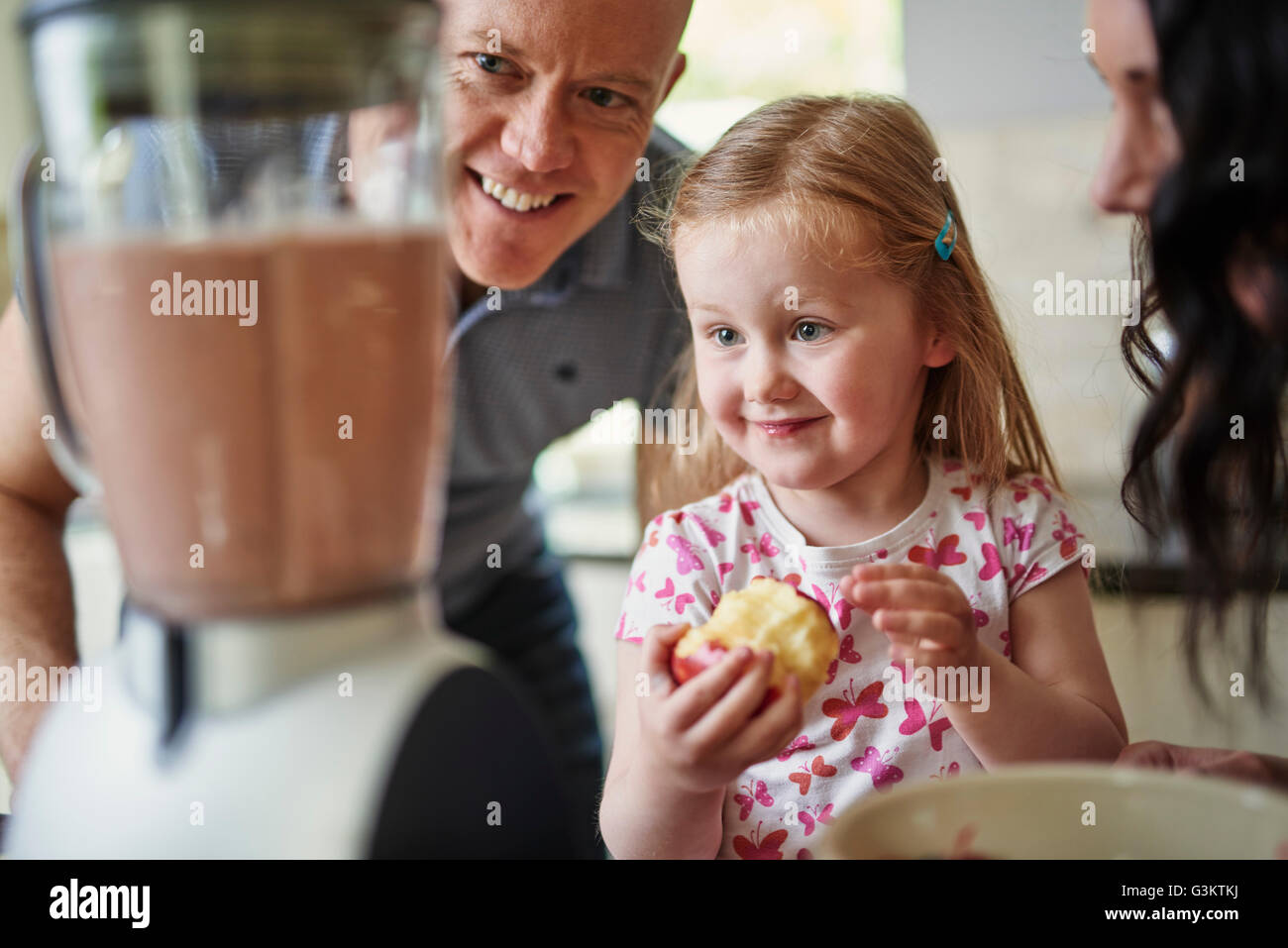 Famiglia guardando i frullati in Blender sorridente Foto Stock