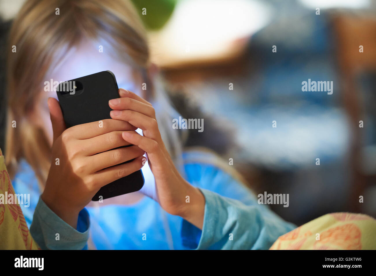 Ragazza giovane guardando smartphone, viso illuminato da candele dello schermo Foto Stock