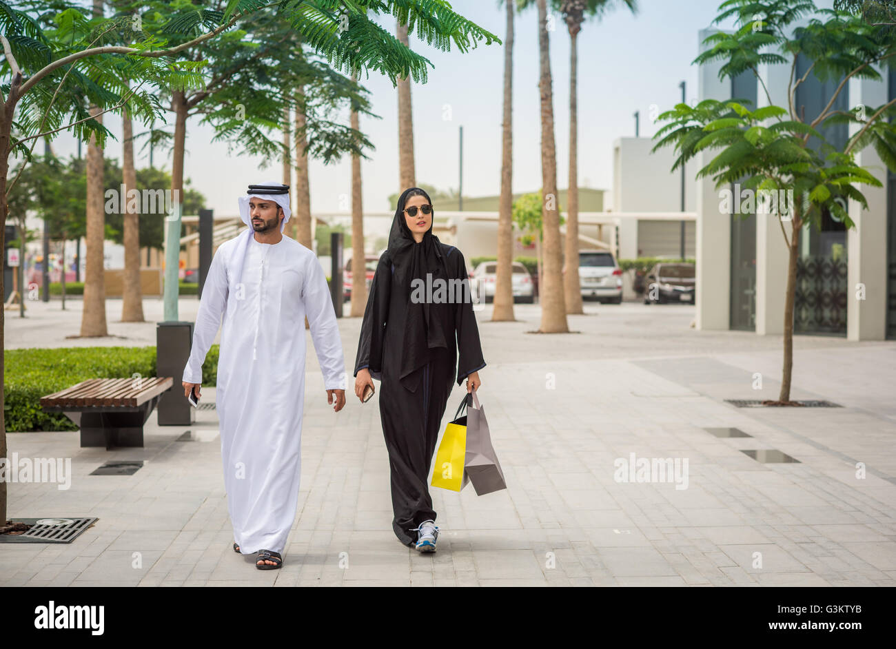 Medio orientale coppia shopping indossando abiti tradizionali a piedi lungo  street, Dubai, Emirati Arabi Uniti Foto stock - Alamy