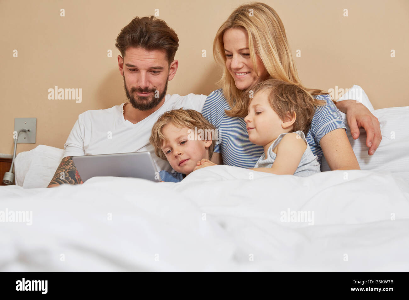 Il padre e la madre a letto con figli guardando a tavoletta digitale Foto Stock