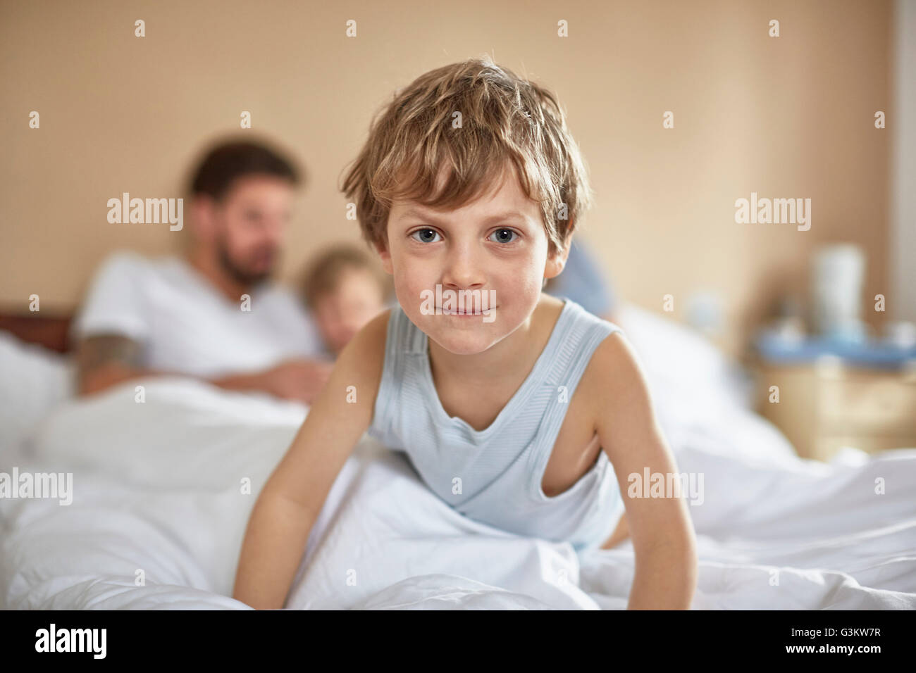 Ragazzo sul letto dei genitori guardando sorridente della fotocamera Foto Stock