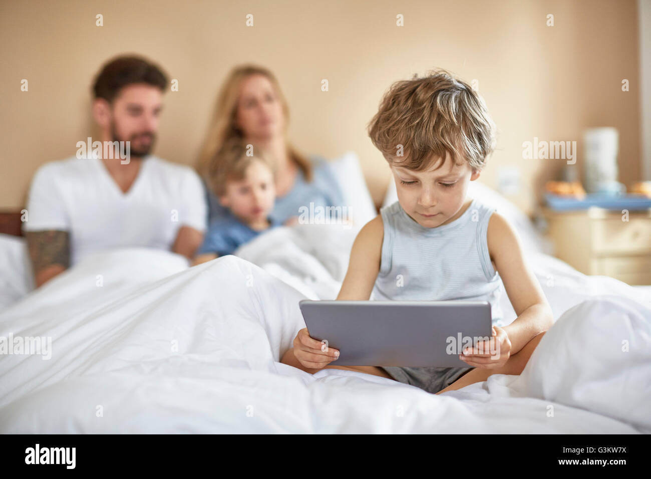 Bambino in camera con i genitori utilizzando tavoletta digitale Foto Stock