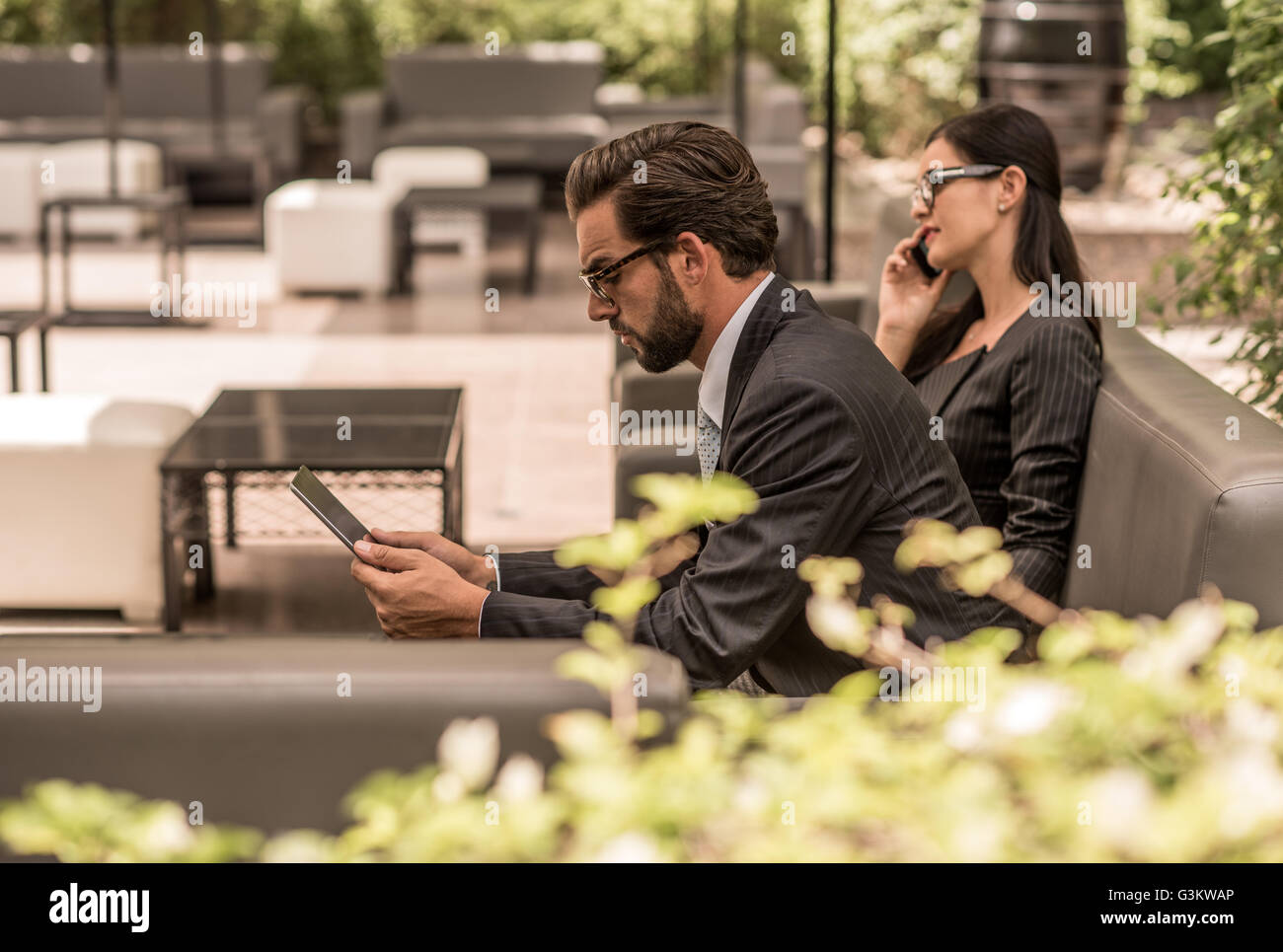 Imprenditore con tavoletta digitale su hotel divano da giardino, Dubai, Emirati Arabi Uniti Foto Stock
