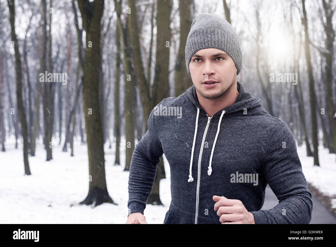 Giovane uomo jogging attraverso boschi innevati Foto Stock