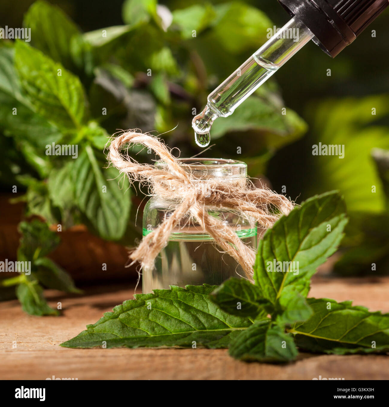 Aroma essenziale con olio di menta piperita su sfondo di legno. Messa a fuoco selettiva, orizzontale. Foto Stock