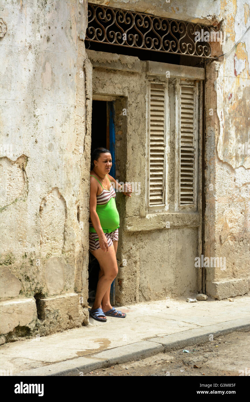 Una donna sta alla porta di una corsa verso il basso casa nella Vecchia Havana, Cuba Foto Stock