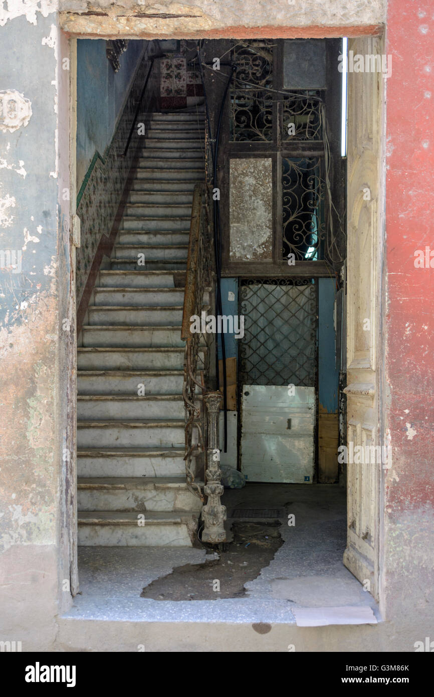 Una porta aperta su una vecchia casa rivela il buio interiore e scale, Old Havana, Cuba Foto Stock