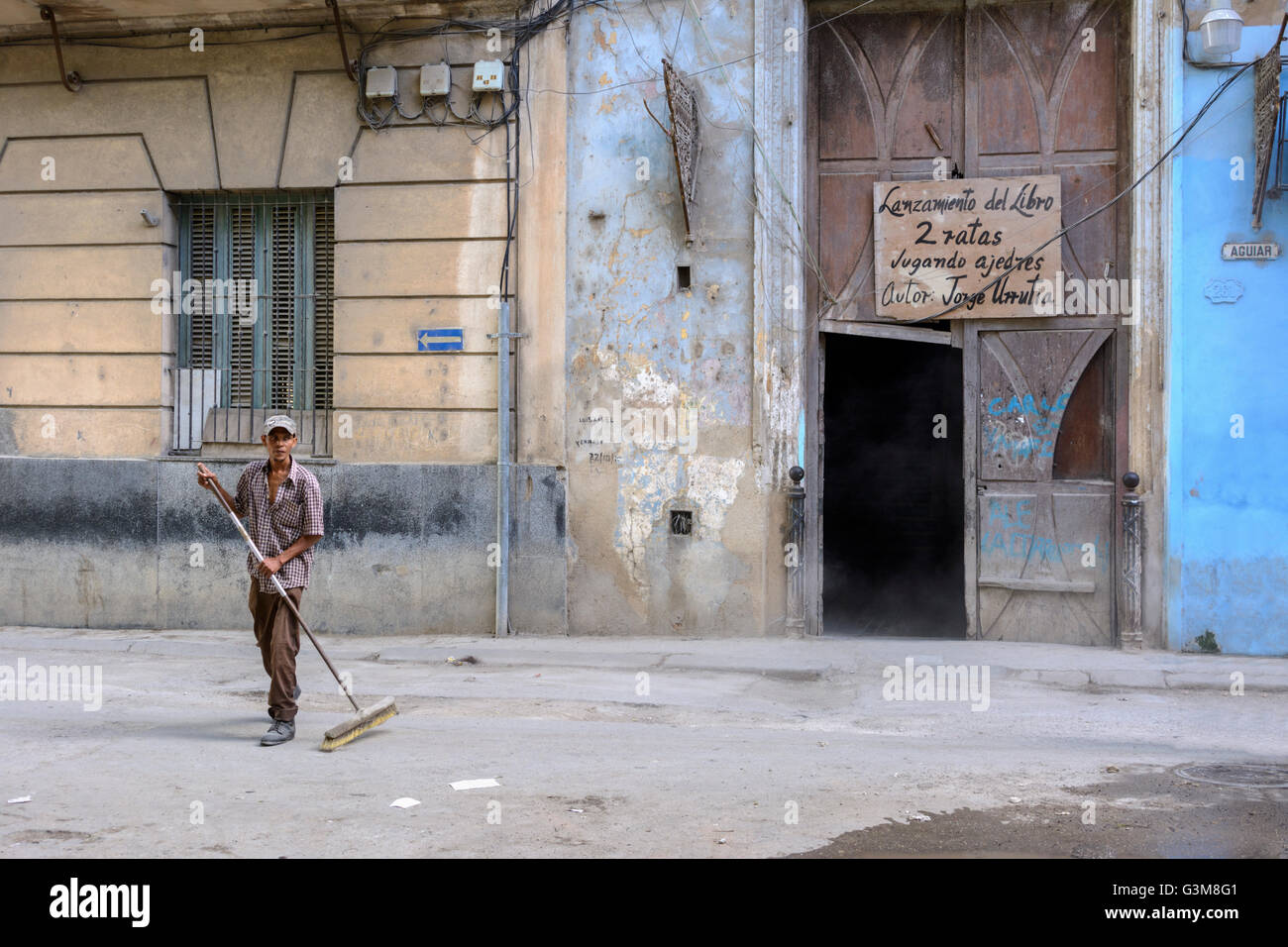 Un uomo cubano spazza le strade nella parte anteriore di una tradizionale facciata di edificio in Old Havana, Cuba Foto Stock