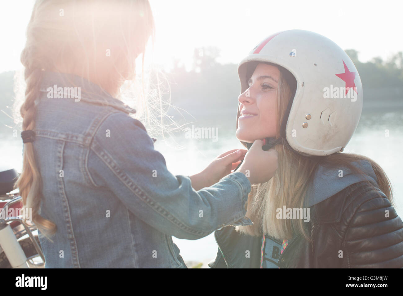 Ragazza giovane aiutando la madre mettere sul casco Foto Stock