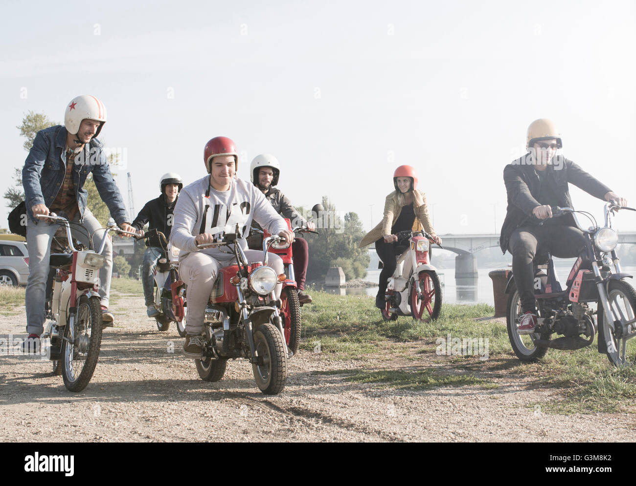 Gruppo di amici in sella ciclomotori accanto al lago Foto Stock