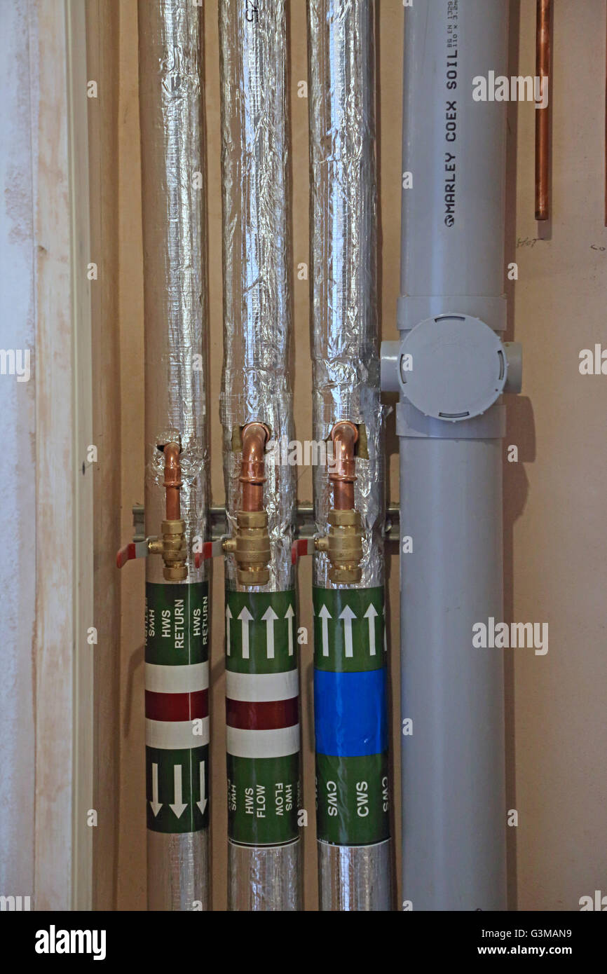 Acqua calda e tubi di drenaggio in un condotto di servizio di un nuovo sviluppo residenziale in Essex, Regno Unito Foto Stock