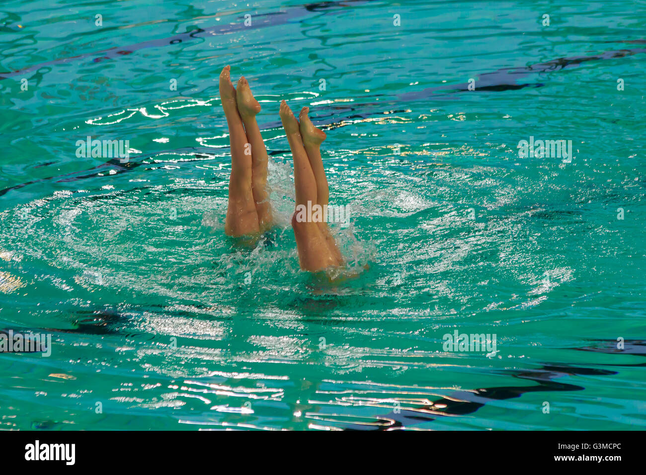Due atleti nuoto sincronizzato durante una competizione in esecuzione un rialzo rimanendo in apnea con le gambe e i piedi al di fuori dell'acqua Foto Stock