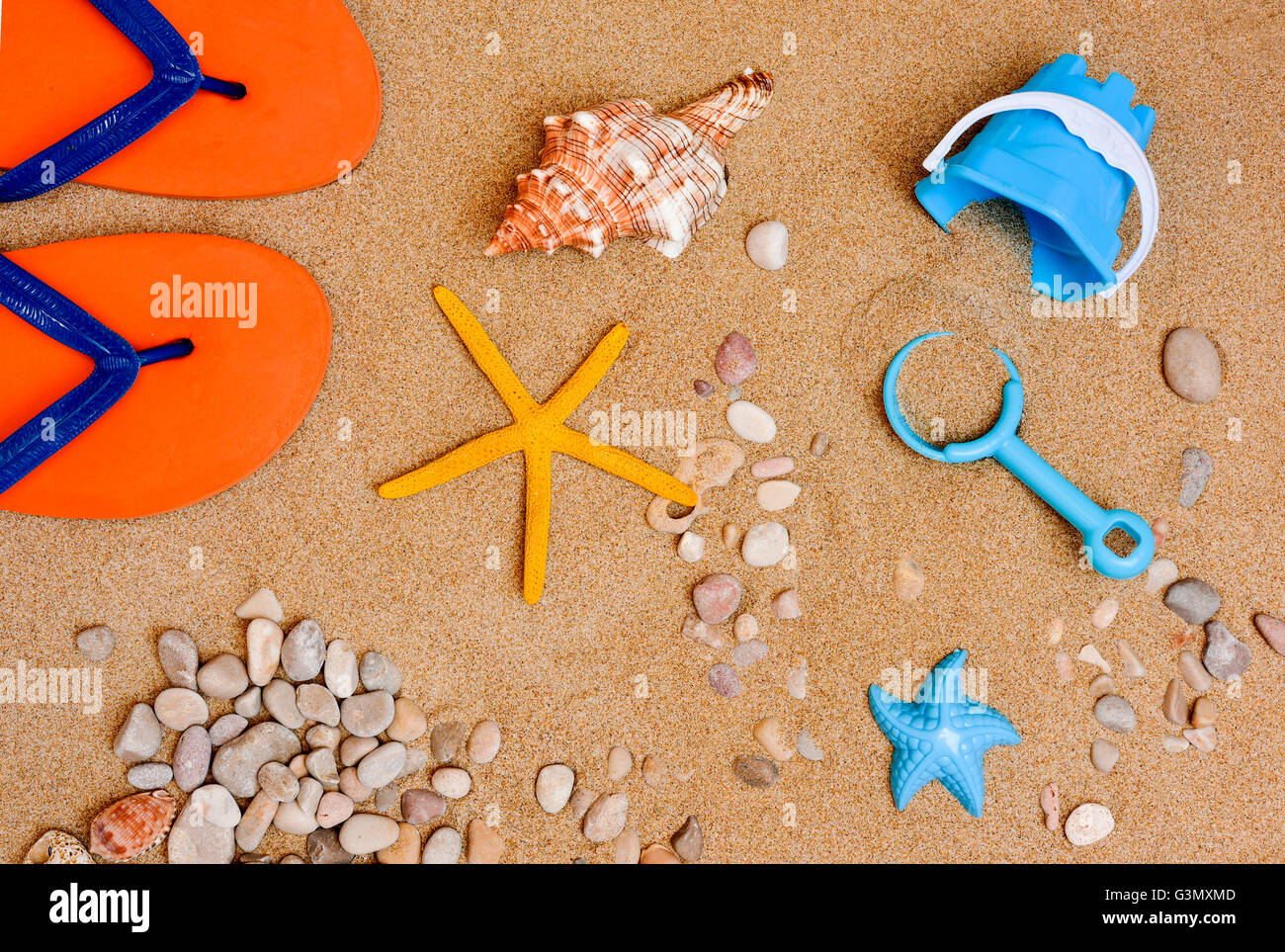Alta angolazione di alcune cose di estate, ad una coppia di flip-flop, una conchiglia, una stella di mare, dei ciottoli e conchiglie o un piccolo beac Foto Stock