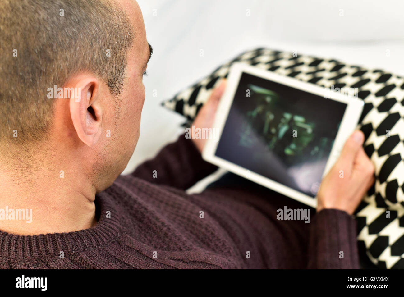 Un giovane uomo caucasico sdraiato sul divano guardando un film o una serie in streaming nel suo computer tablet Foto Stock