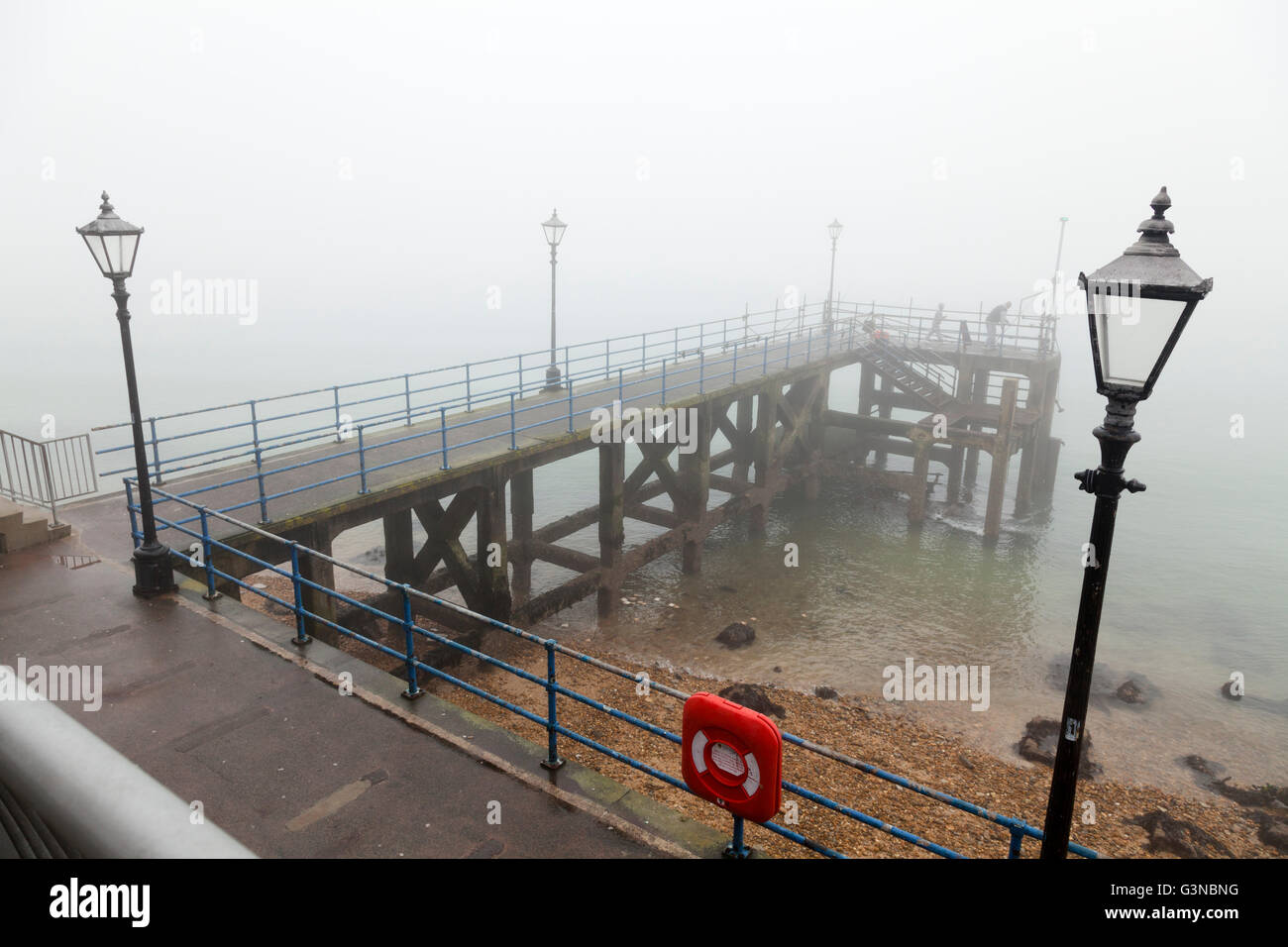 Portsmouth pier / pontile con lampade stradali e salvagente nella nebbia Foto Stock