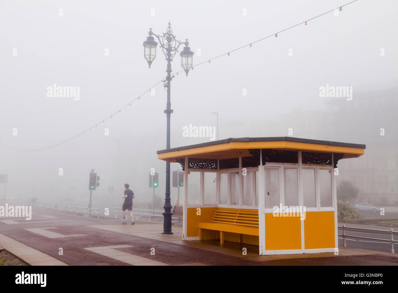 Jogging nella nebbia sul lungomare in inverno passato un rifugio Foto Stock