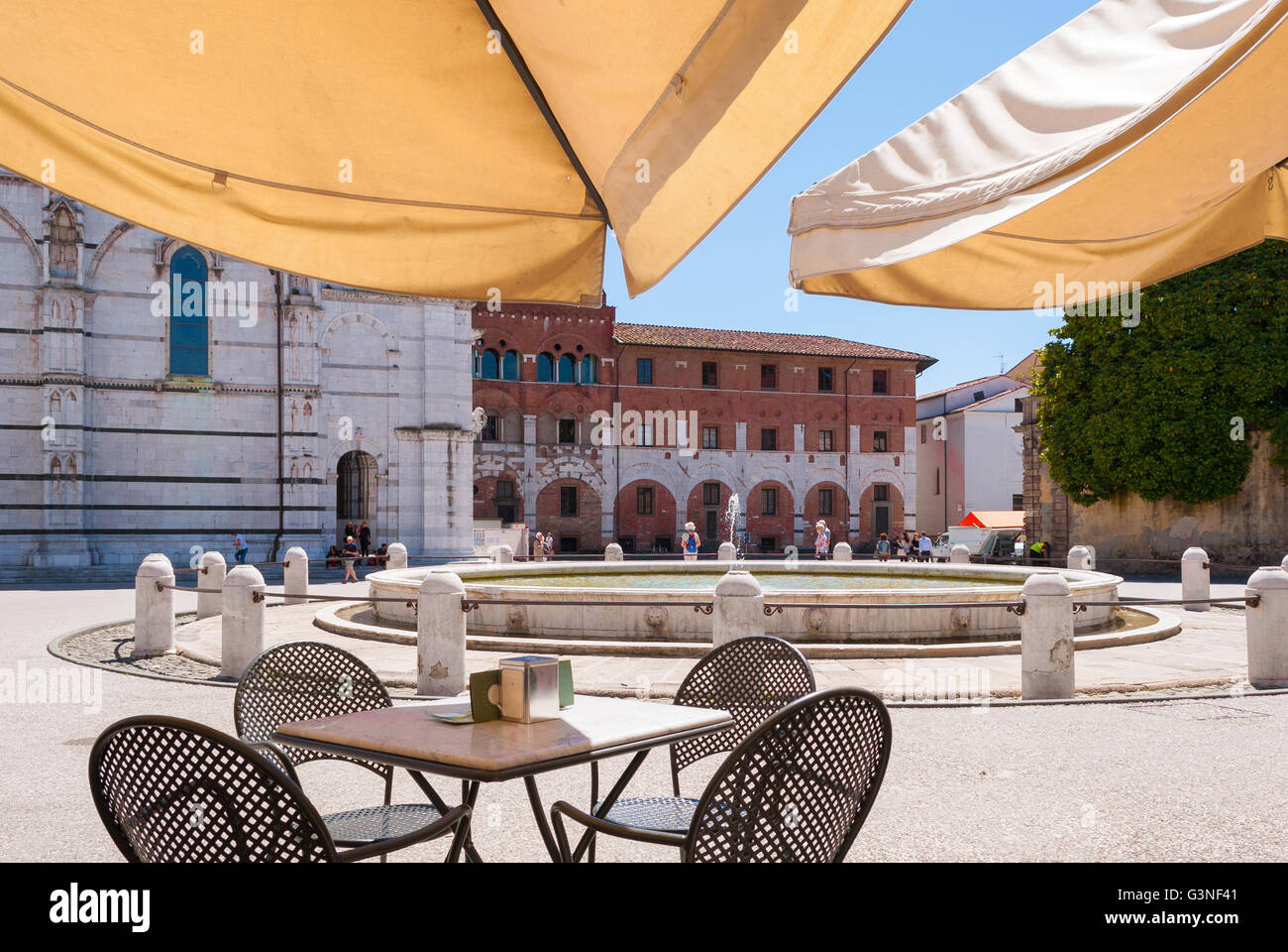 La tabella di un bar sotto un ombrellone in una piazza di Lucca Foto Stock