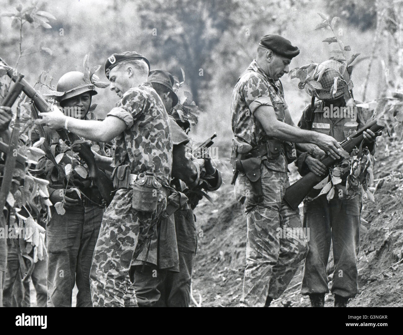 Noi Green Beret truppe vietnamita in treno - Istruzioni per la precisione di tiro con live munizioni è dato del Vietnam del Sud le truppe nativo da Sgt. Stanley Harold, sinistra e Capt Robert Lopez del dalle Forze Speciali americane. A causa del rapido aumento delle dimensioni di questo corpo, ufficiali ora sono assegnati su un "non-volontario " base, ma uomini arruolati sono ancora tutti volontari. Foto Stock