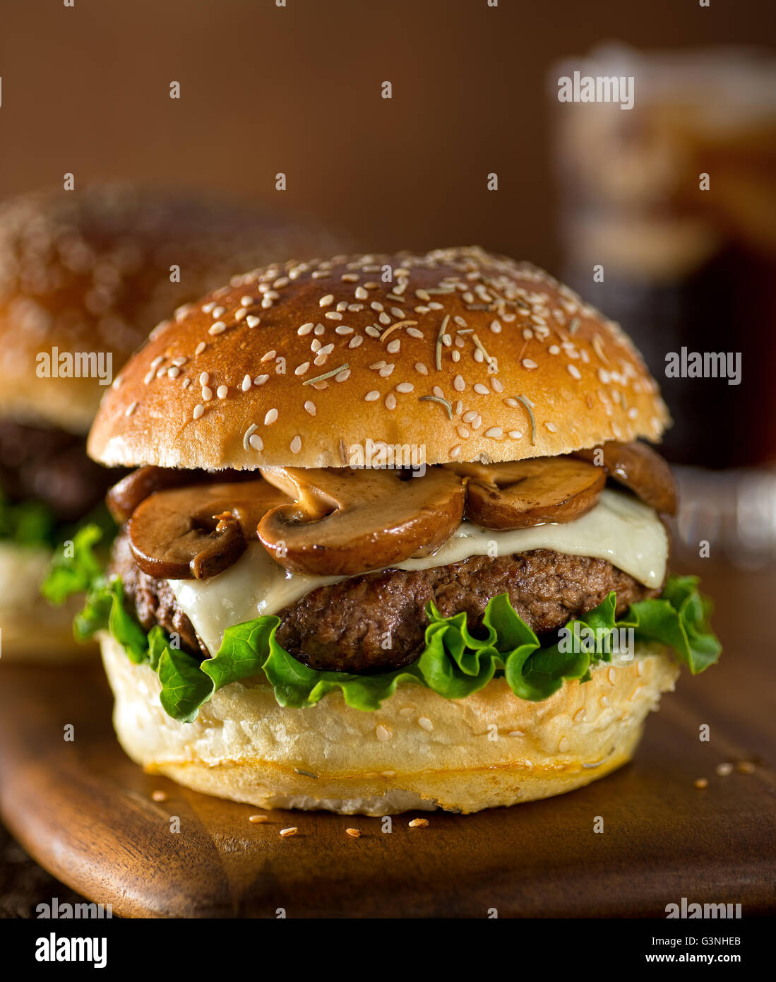 Un delizioso hamburger gourmet conditi con formaggio svizzero e Funghi Fritti su un rosmarino semi di sesamo bun. Foto Stock