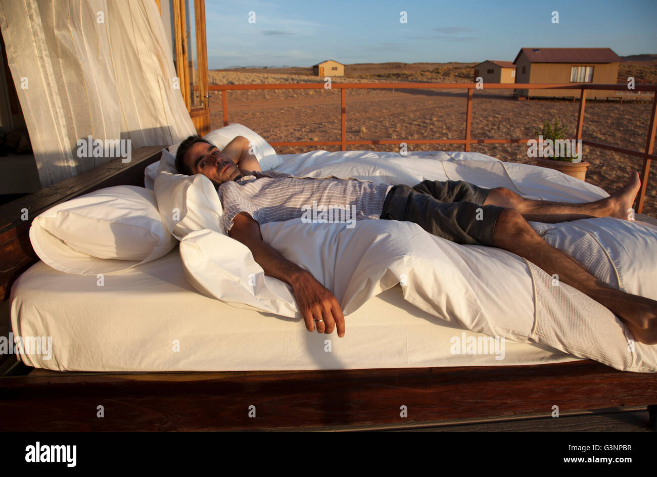 L'uomo sul letto al deserto del Namib Star Dune Camp in Namibia Foto Stock